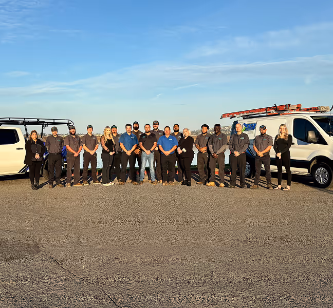 Work team poses together with service vehicles under blue sky
