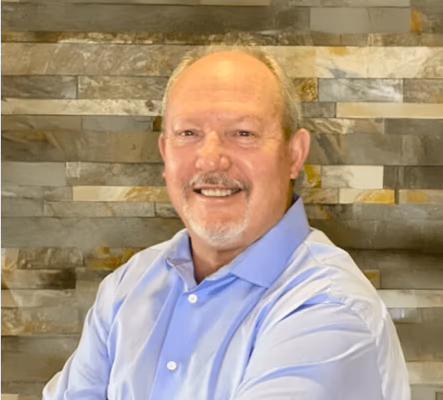 Smiling older man in blue shirt against stone wall background