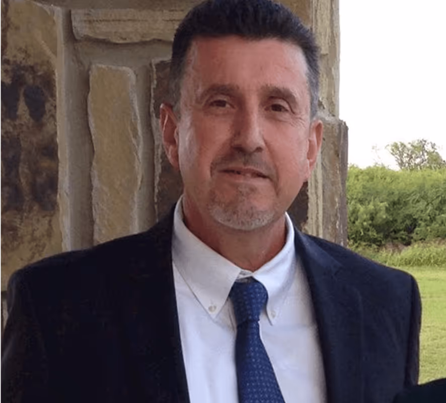 Middle-aged professional in suit and tie standing near stone wall outdoors