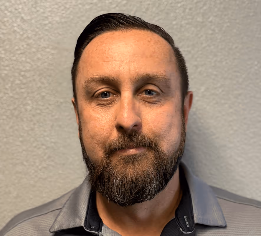 Bearded man in gray jacket looking directly at camera