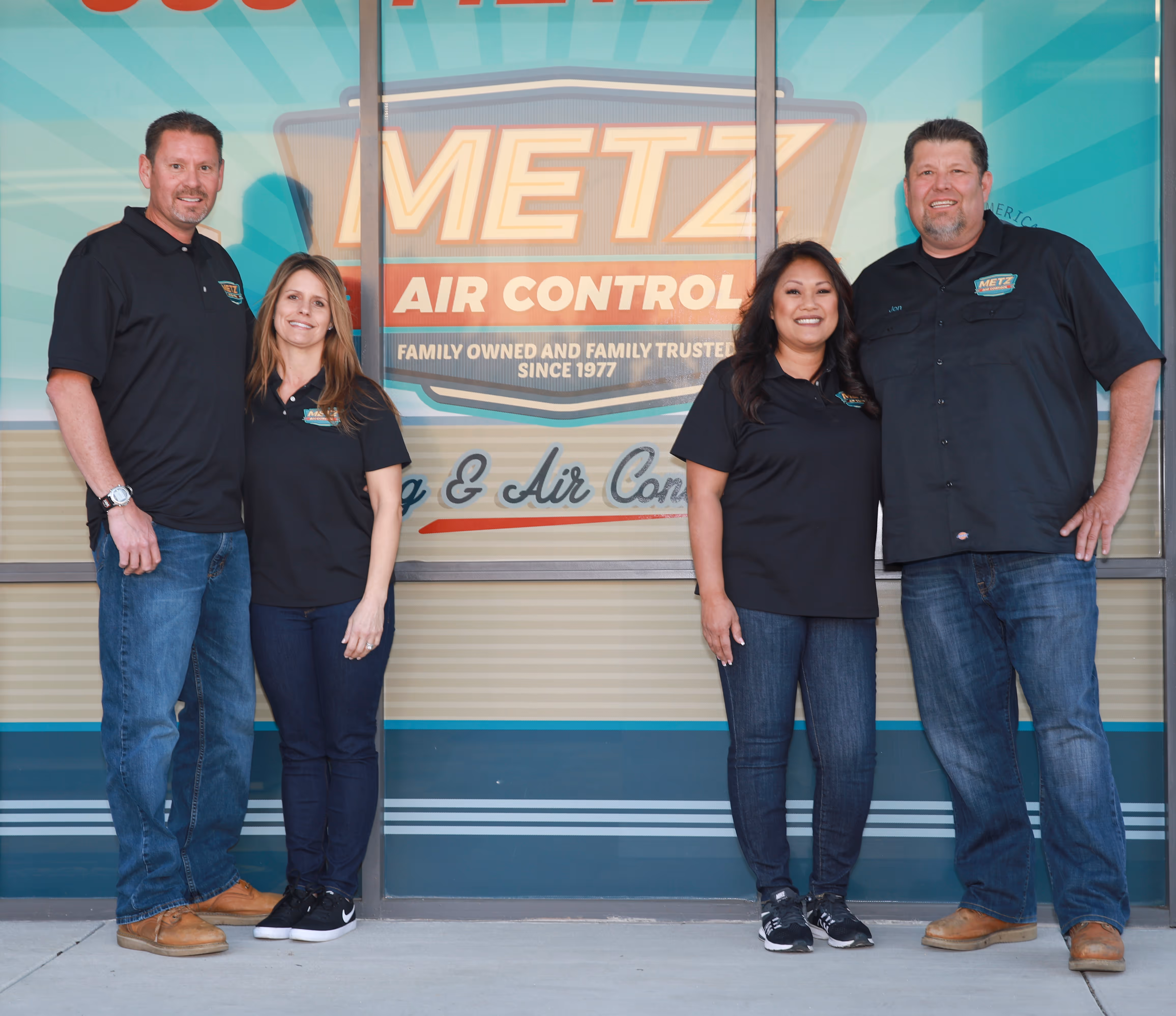 Four Metz Air Control employees posing in front of company sign
