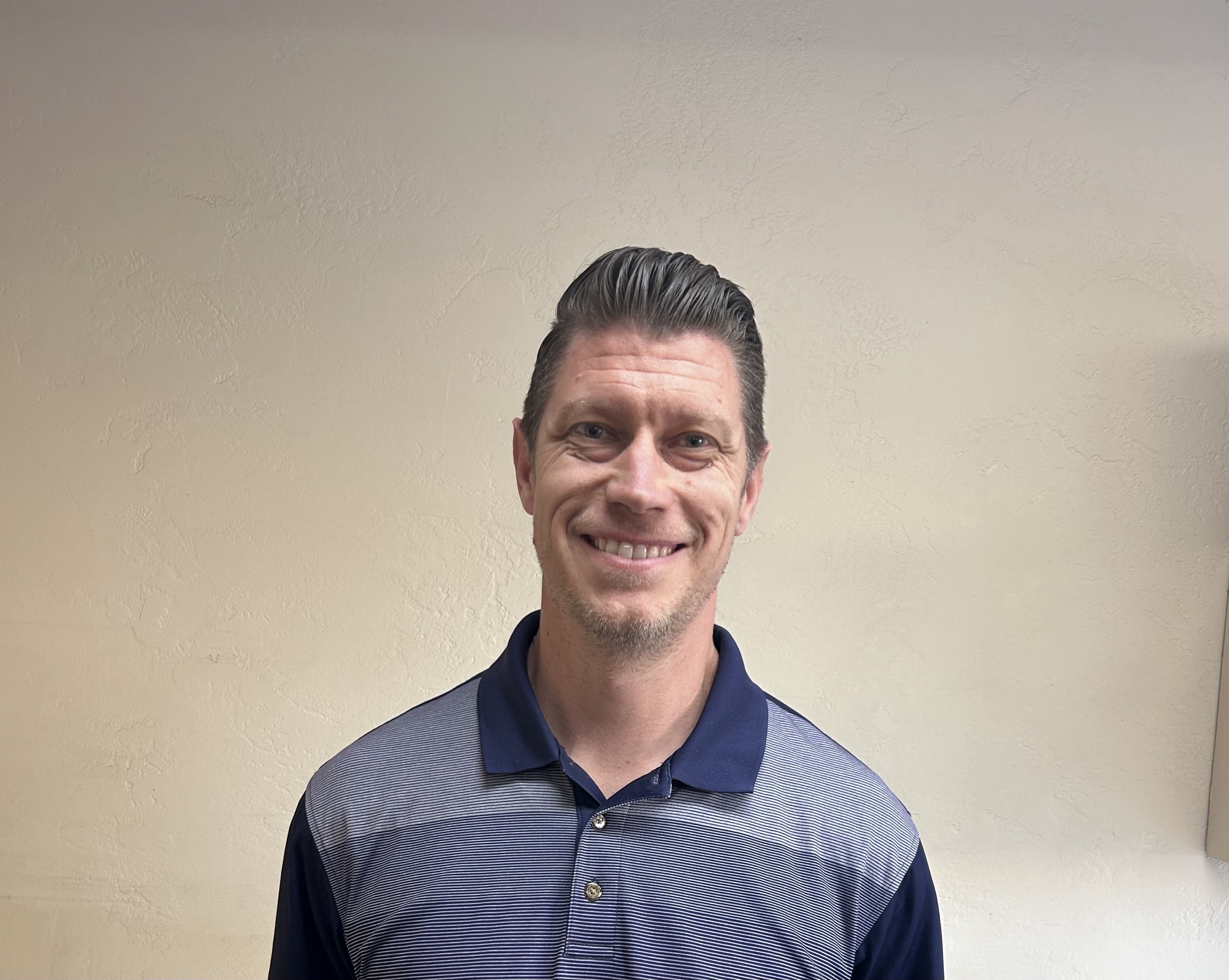 Smiling middle-aged man in striped blue polo shirt against neutral background