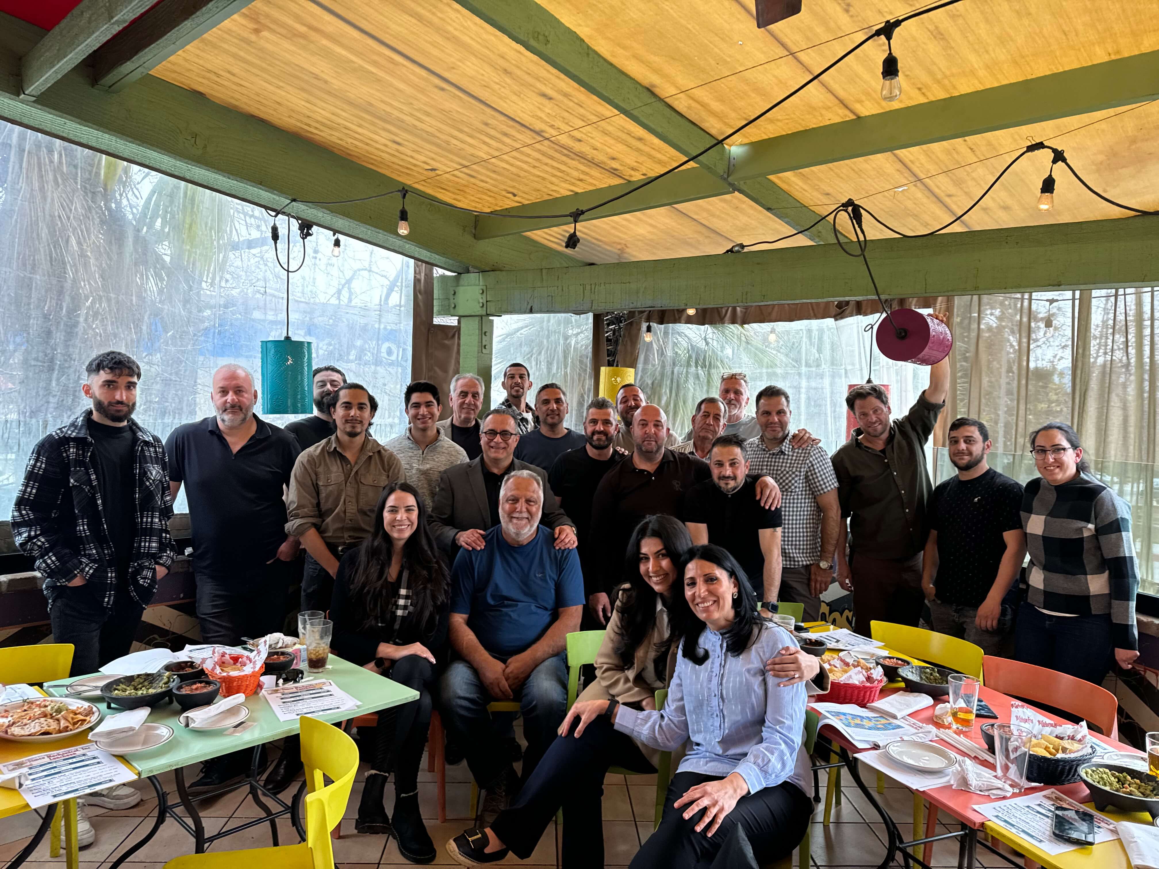 A group of people gathered at a restaurant, smiling and posing for a photo together.