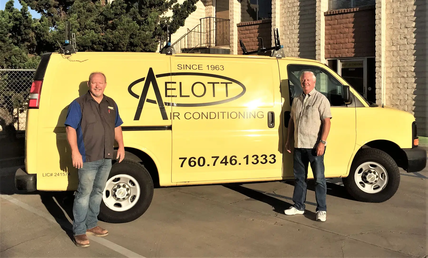 Two men standing in front of a yellow air conditioning service van.