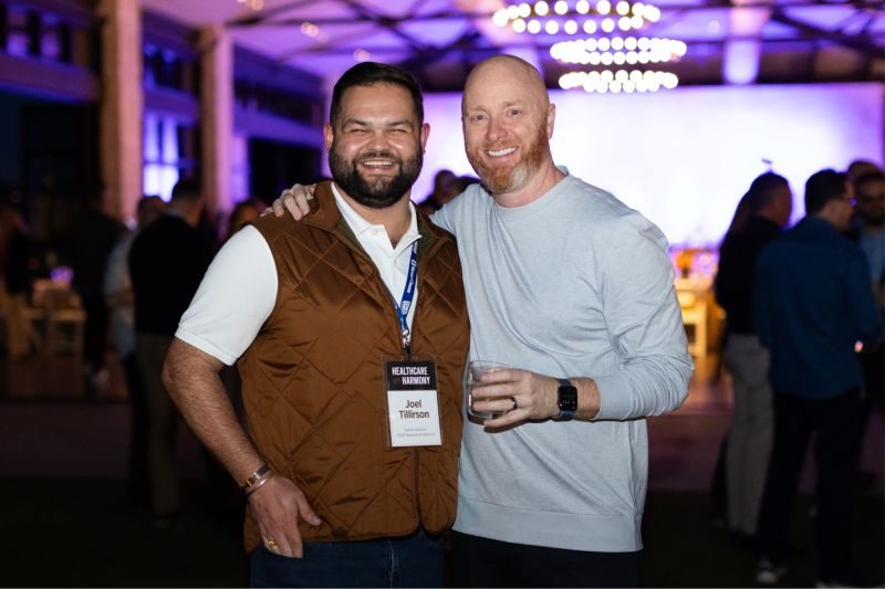 Two men embracing and smiling at a healthcare industry event