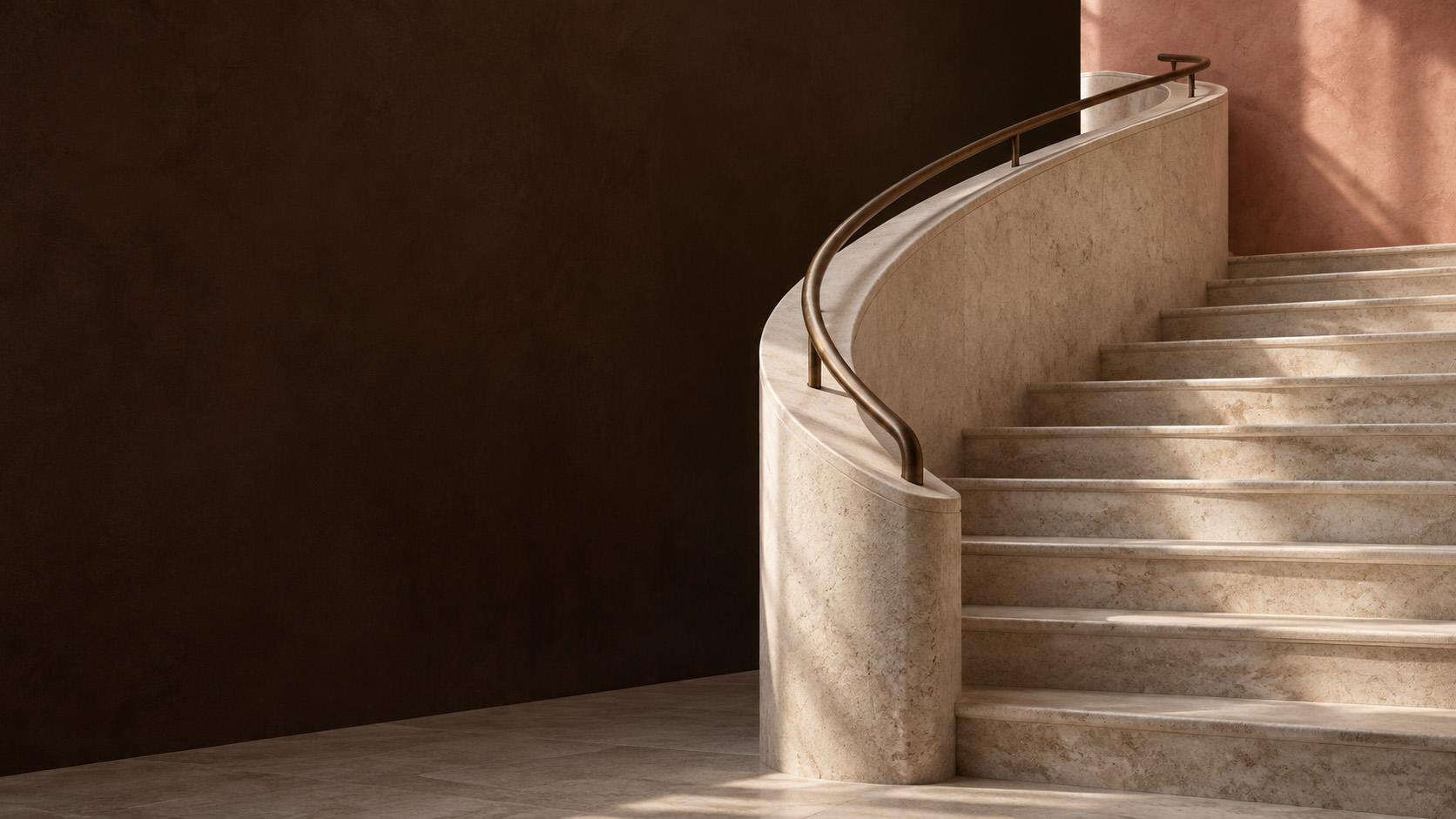 Sweeping stone staircase with a bronze handrail in warm light