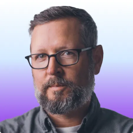 Headshot of a man with glasses, beard, and short dark hair against a blue and purple gradient background.
