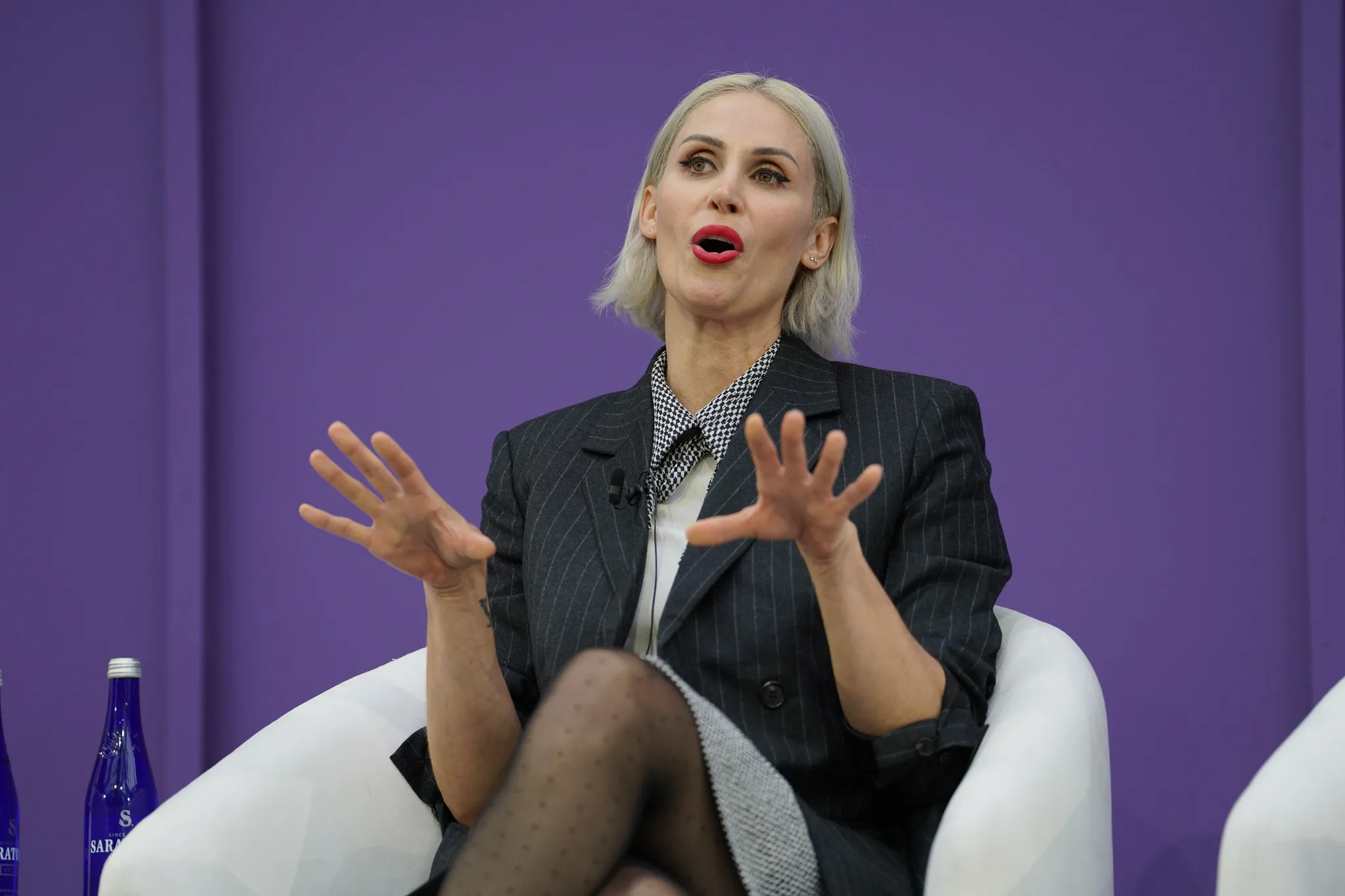 Four panelists seated on stage engaged in discussion, two men and two women.