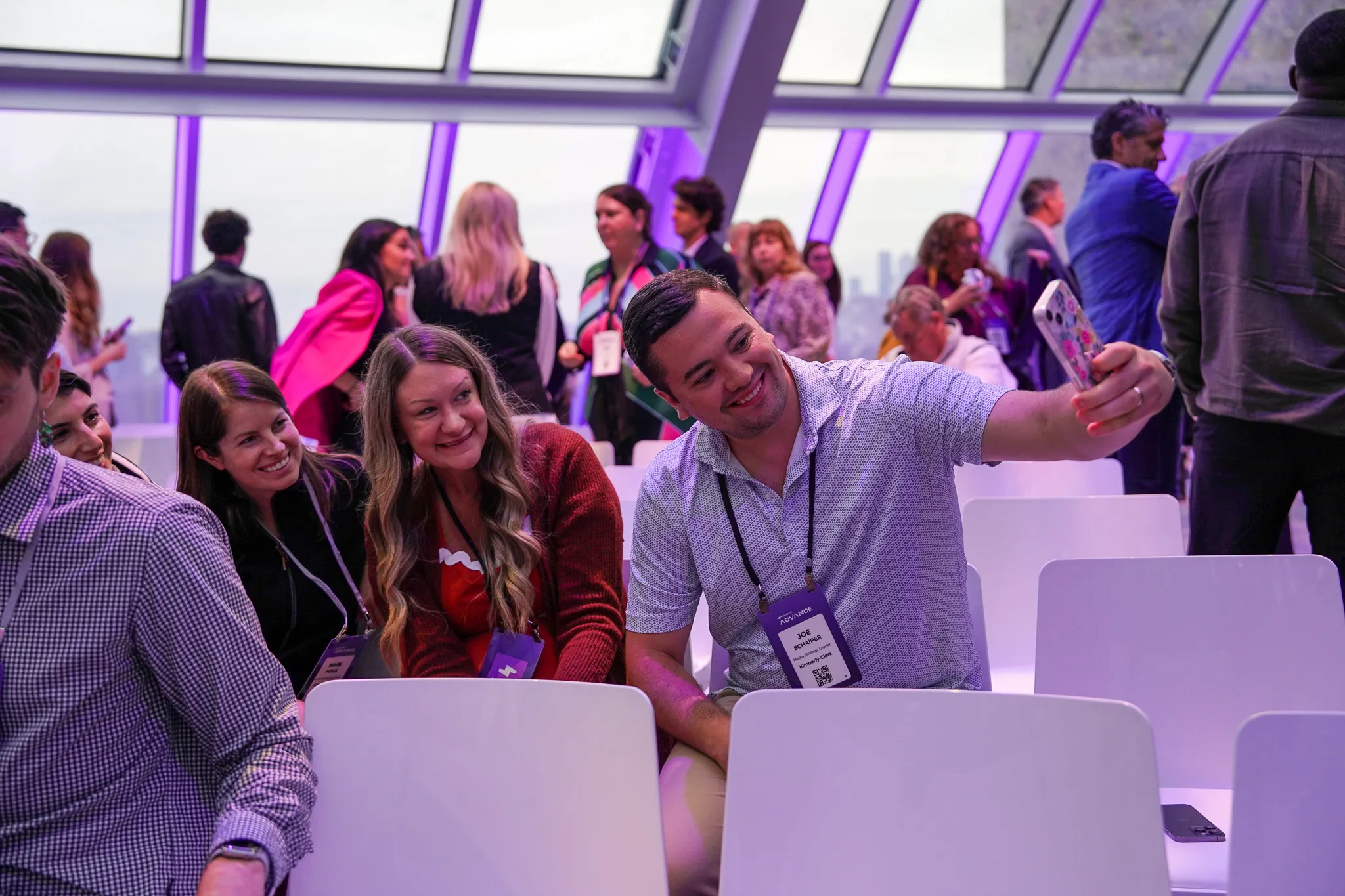 Panel discussion on stage with five speakers seated in front of a purple Smartly Advance backdrop showing their names and titles.