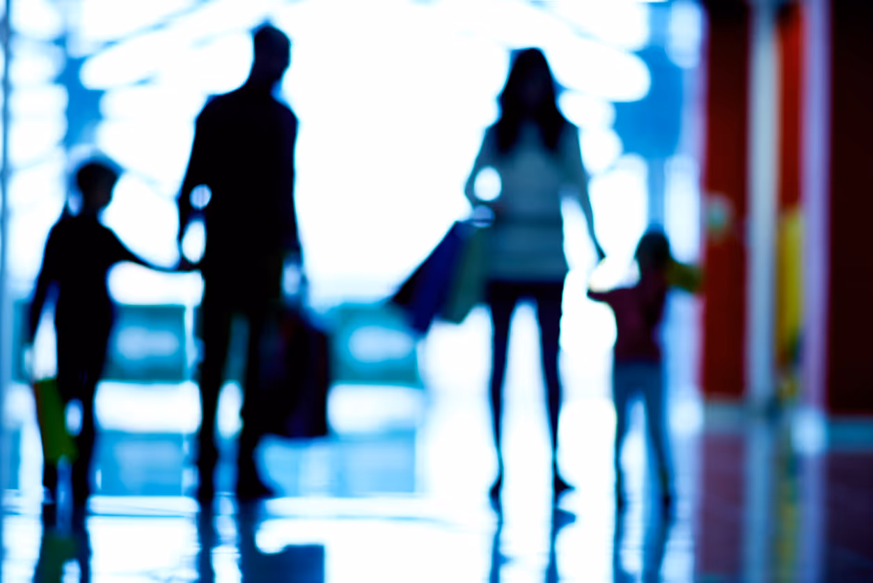 Blurry silhouettes of four people walking together in a bright space