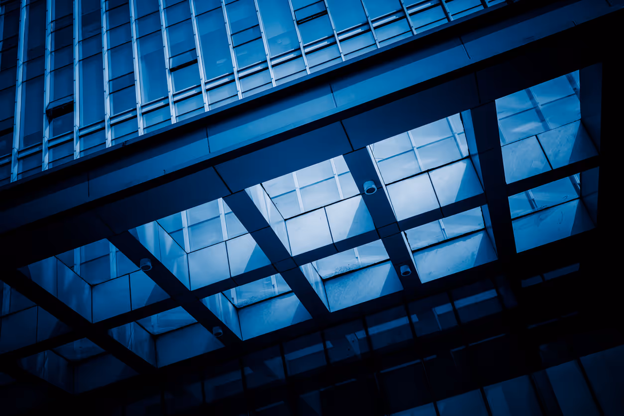 Modern glass architecture with geometric blue-tinted windows and reflections