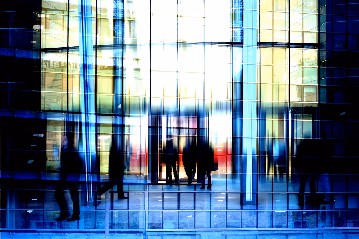 Blurred silhouettes of people in a modern glass building interior