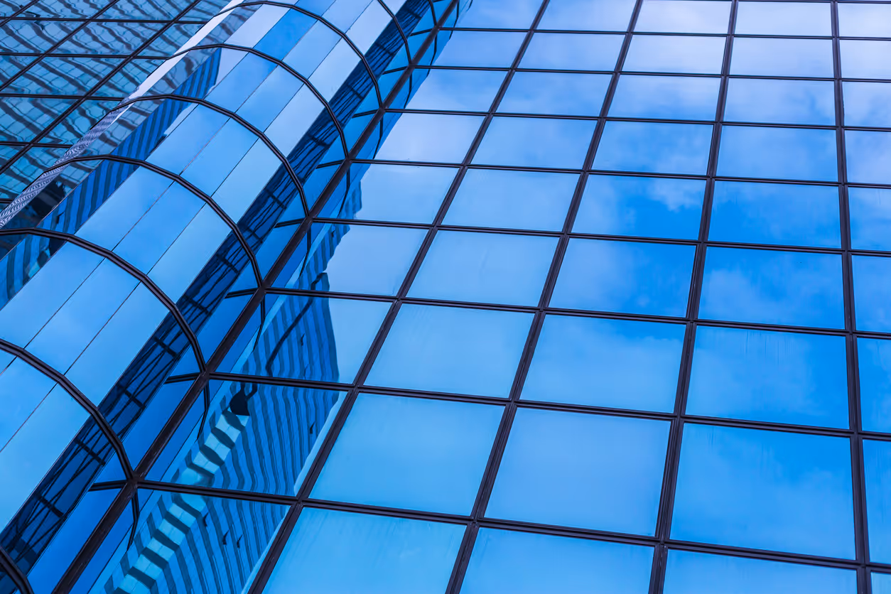 Modern glass skyscraper facade with blue reflective windows and geometric design
