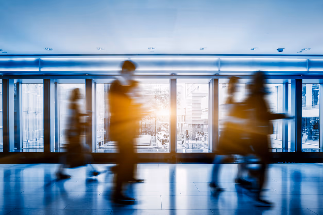 Blurred figures walking in modern office with large windows and city view
