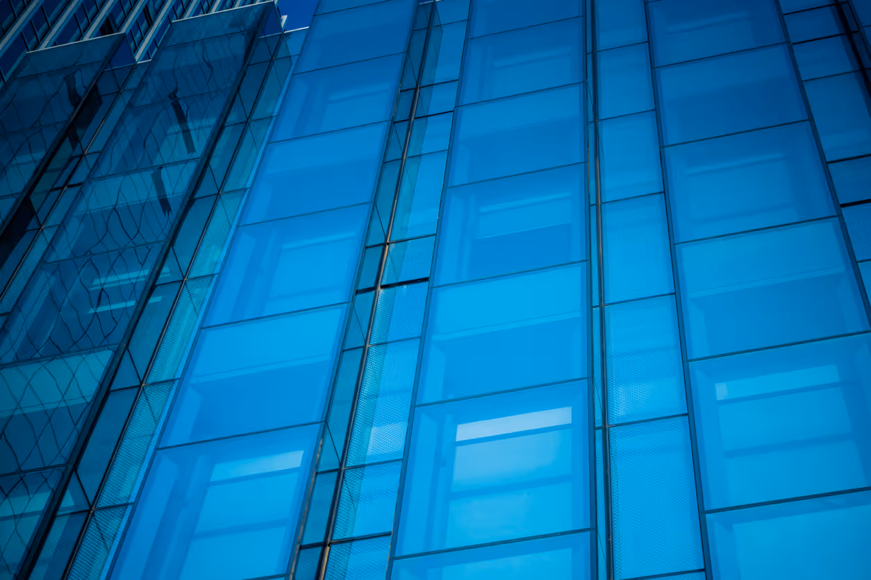 Blue glass facade of modern skyscraper with geometric window patterns