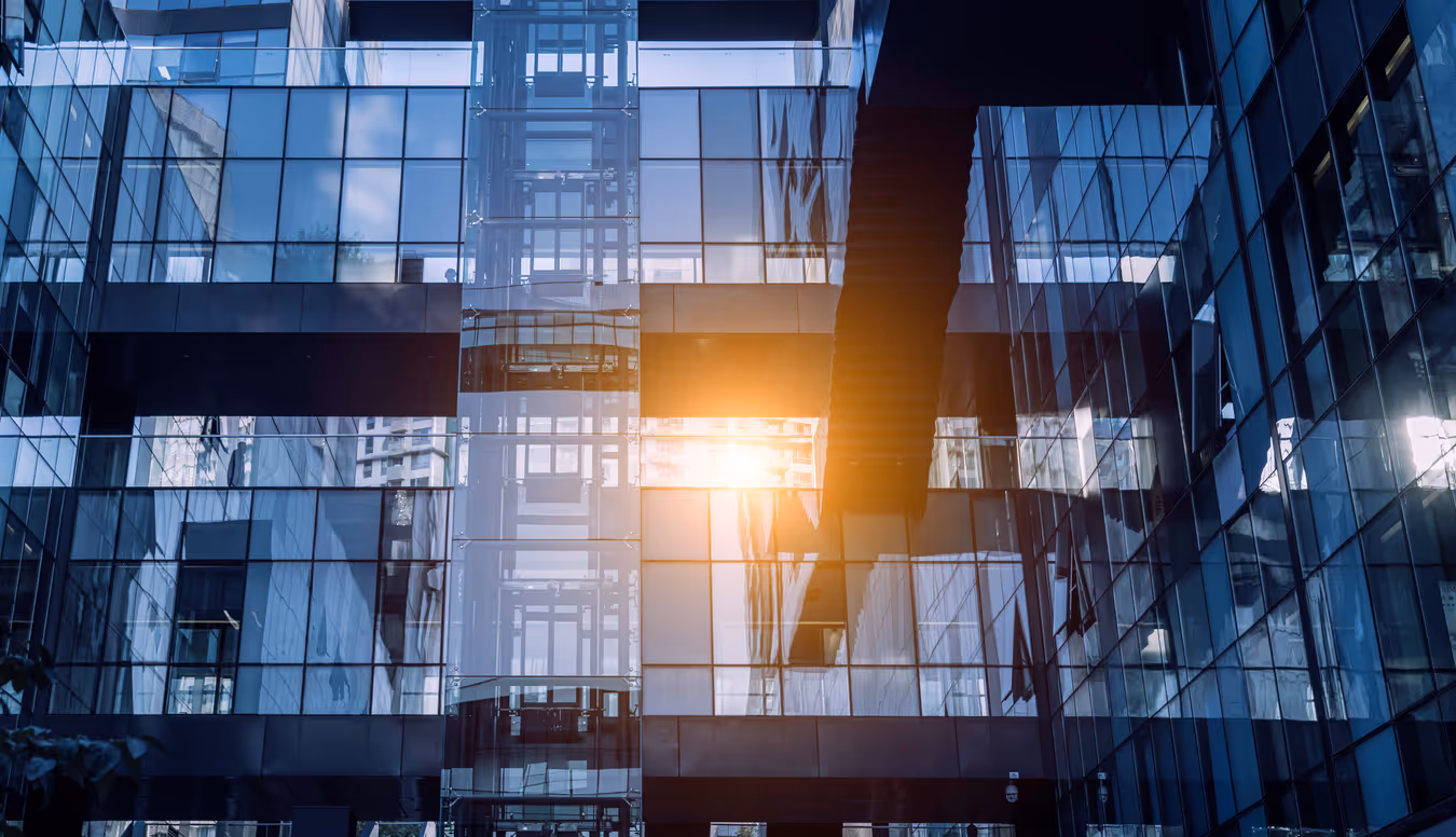 Modern glass office building with sunlight reflecting through windows