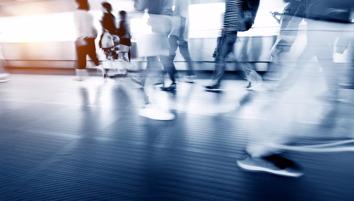 Blurred motion of people walking in a modern, blue-tinted corridor