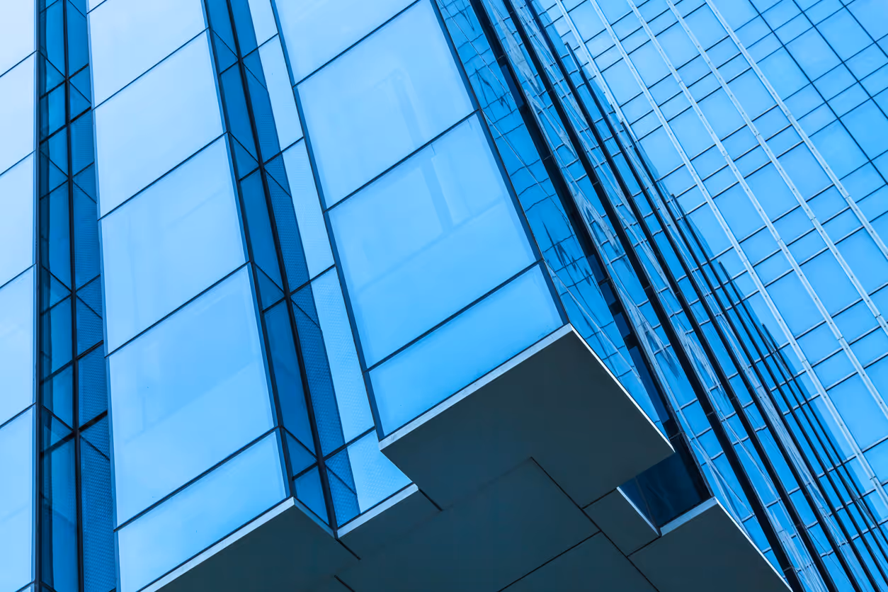 Blue glass skyscraper facade with geometric lines and reflective surfaces