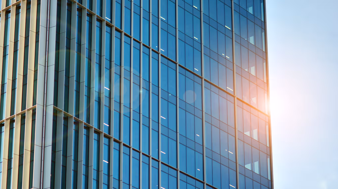 Modern glass office building with blue and golden facade, sunlight reflection
