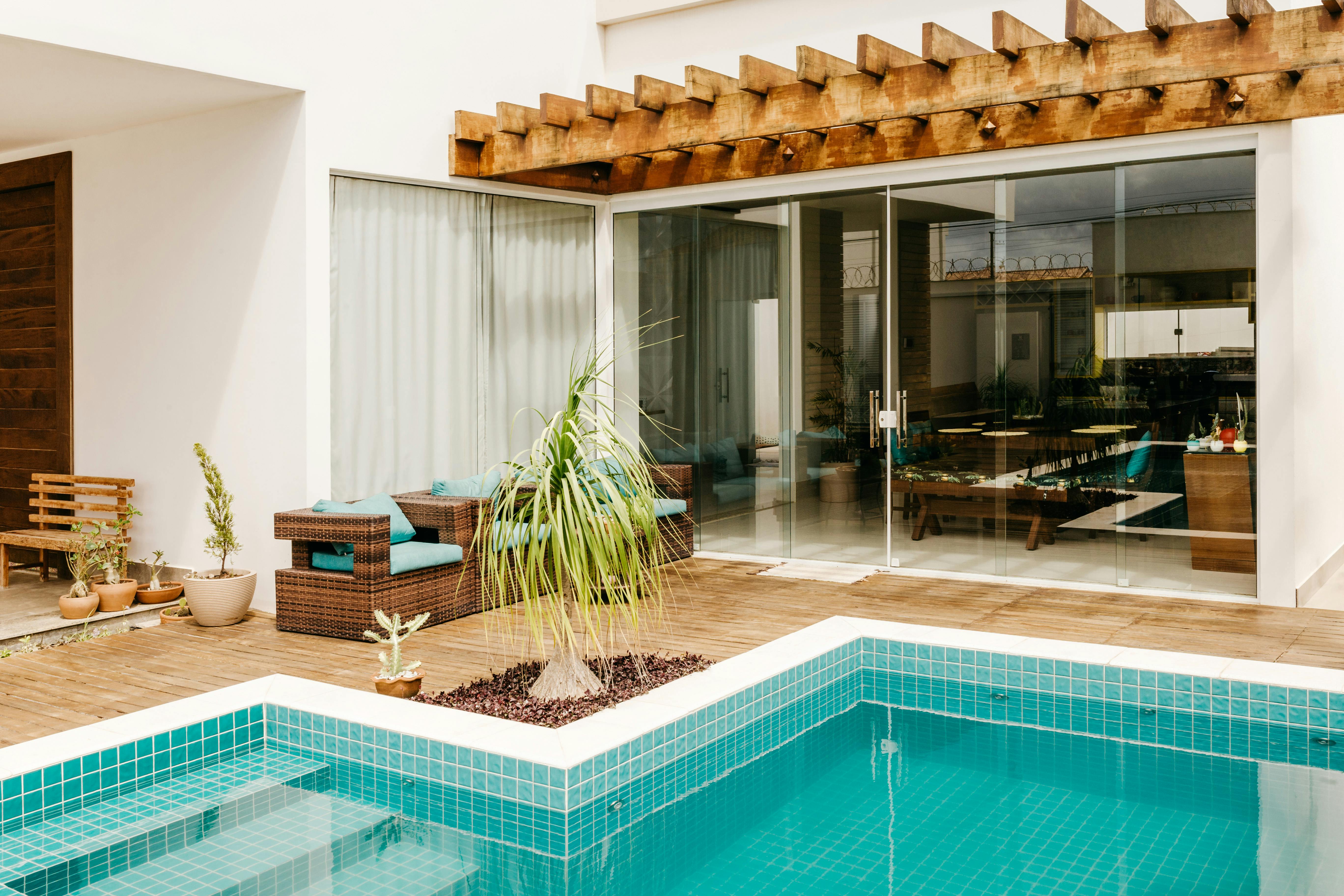 Contemporary poolside patio with elegant seating and lush plants for a relaxing outdoor experience.