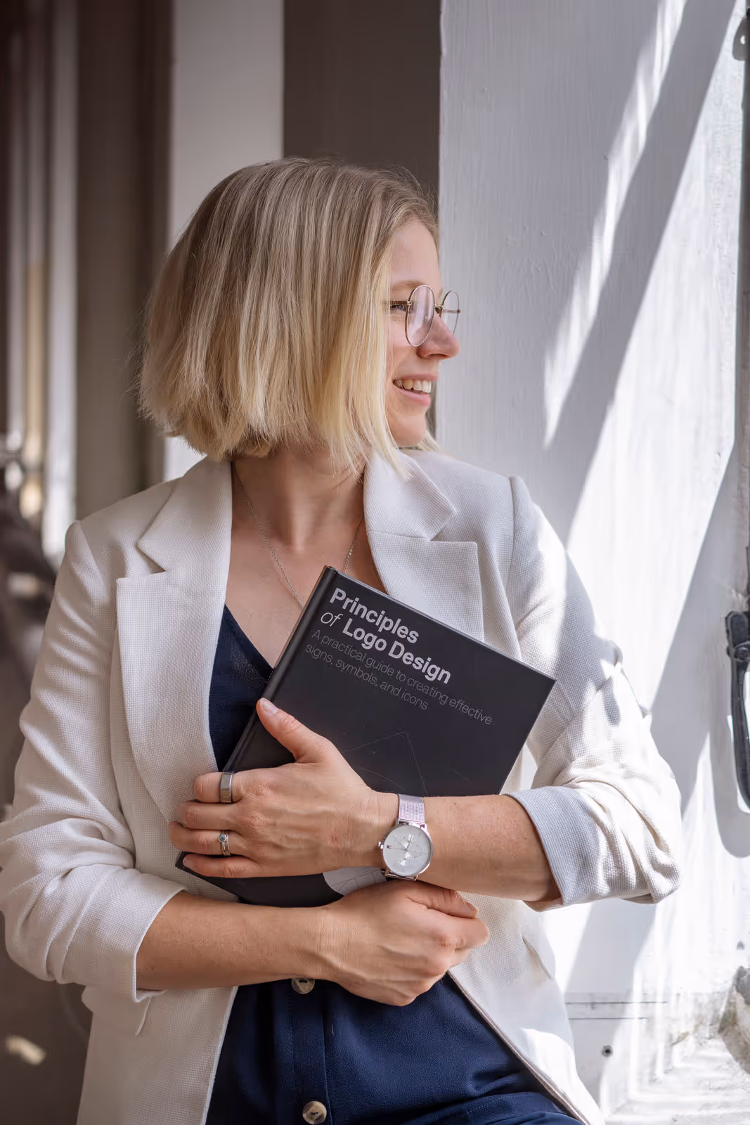 Katrin Schmiedel Inhaberin von KS Branding mit einem Corporate Design Buch in der Hand am Fenster.