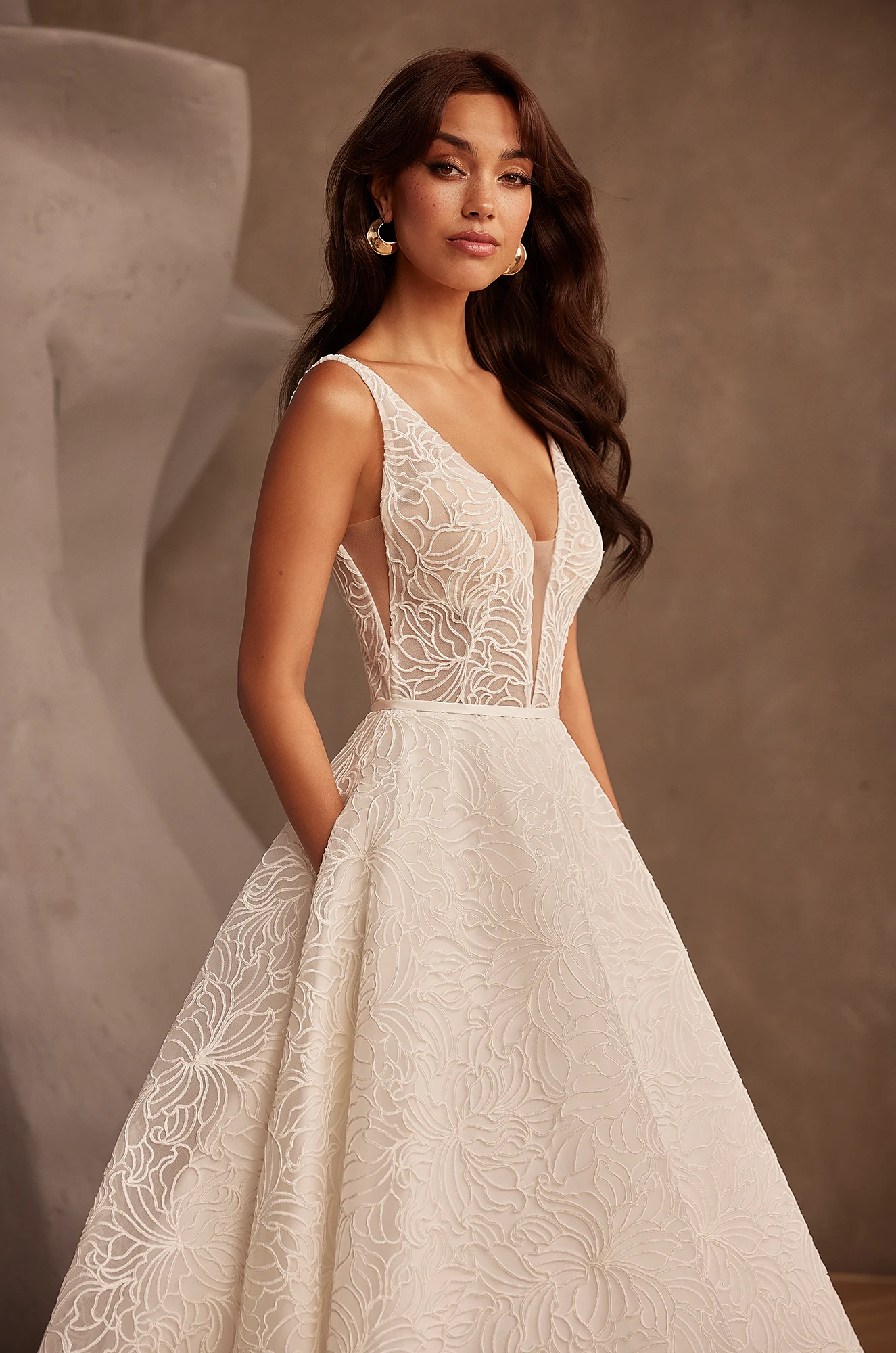 Wedding dress close-up showing V-neckline and detailed tulle floral embroidery pattern.