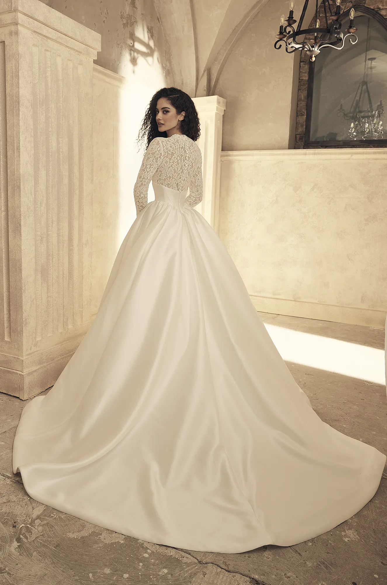 Wedding dress back view showing long sleeve lace detail and flowing ball gown train.