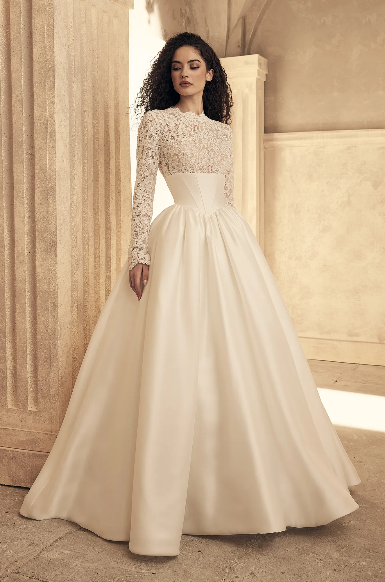 Front view of long sleeve lace wedding dress with fitted bodice, satin skirt and ball gown silhouette.