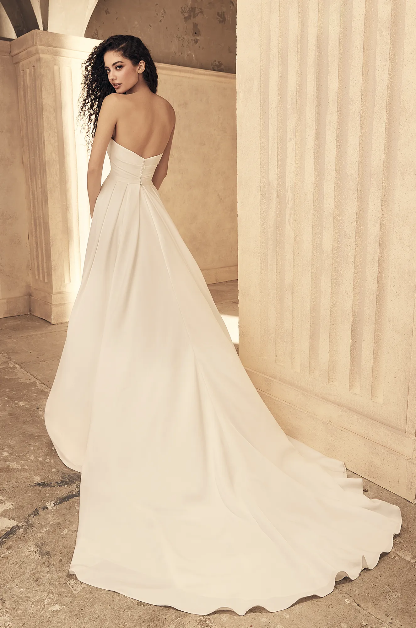 Ivory mermaid wedding dress back view showing strapless design and dramatic sweep train detail.