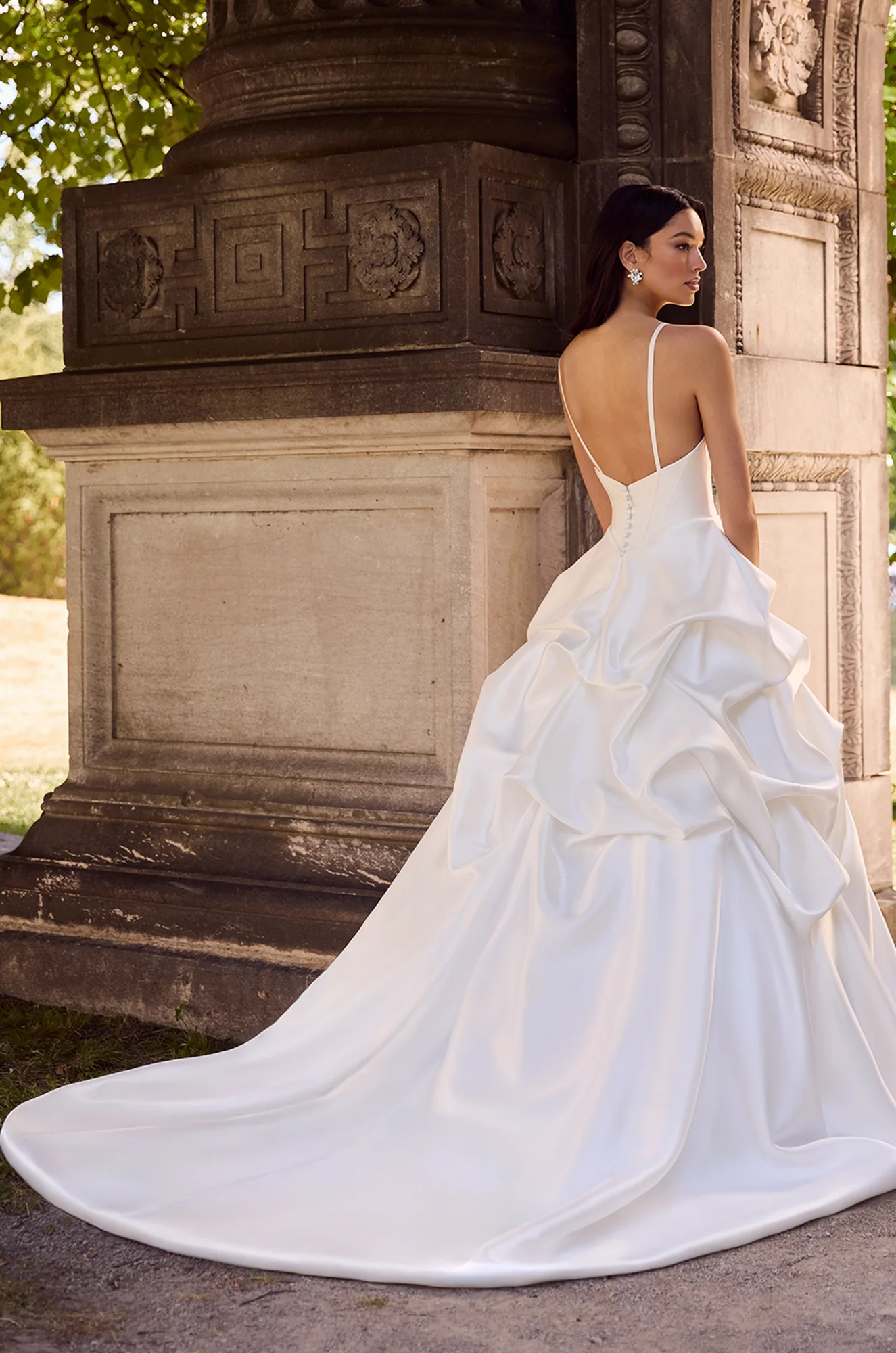 Wedding dress back view showing V-neckline and voluminous ruffled satin ball gown train.