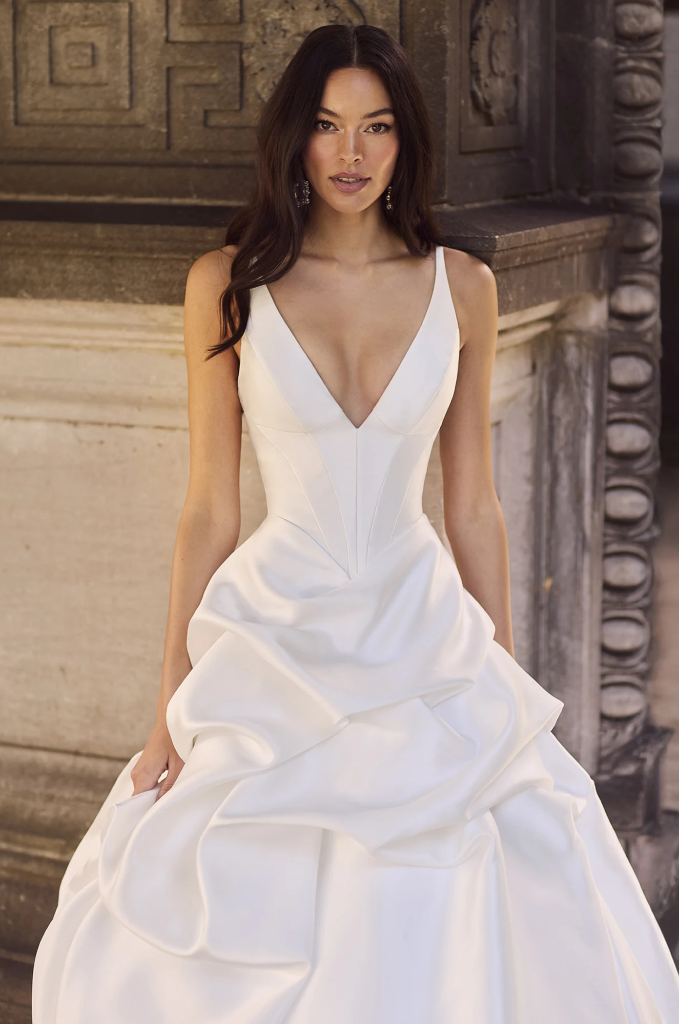 Wedding dress close-up showing V-neckline and fitted satin bodice with ruffle detail.