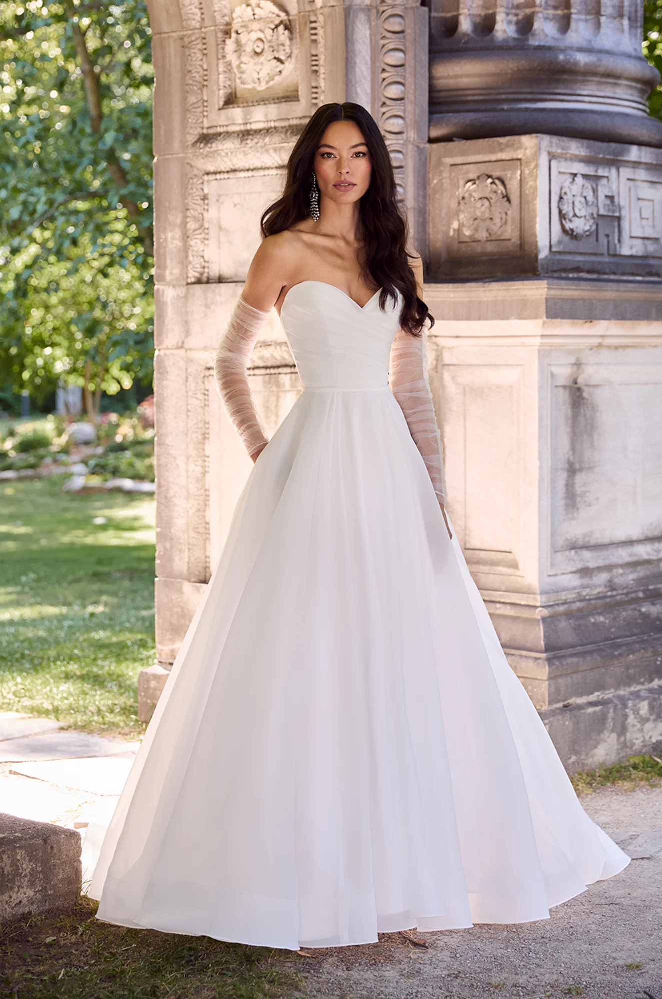 Strapless A-line gown with sweetheart neckline, pleated bodice, and sheer tulle sleeves for a soft romantic look.