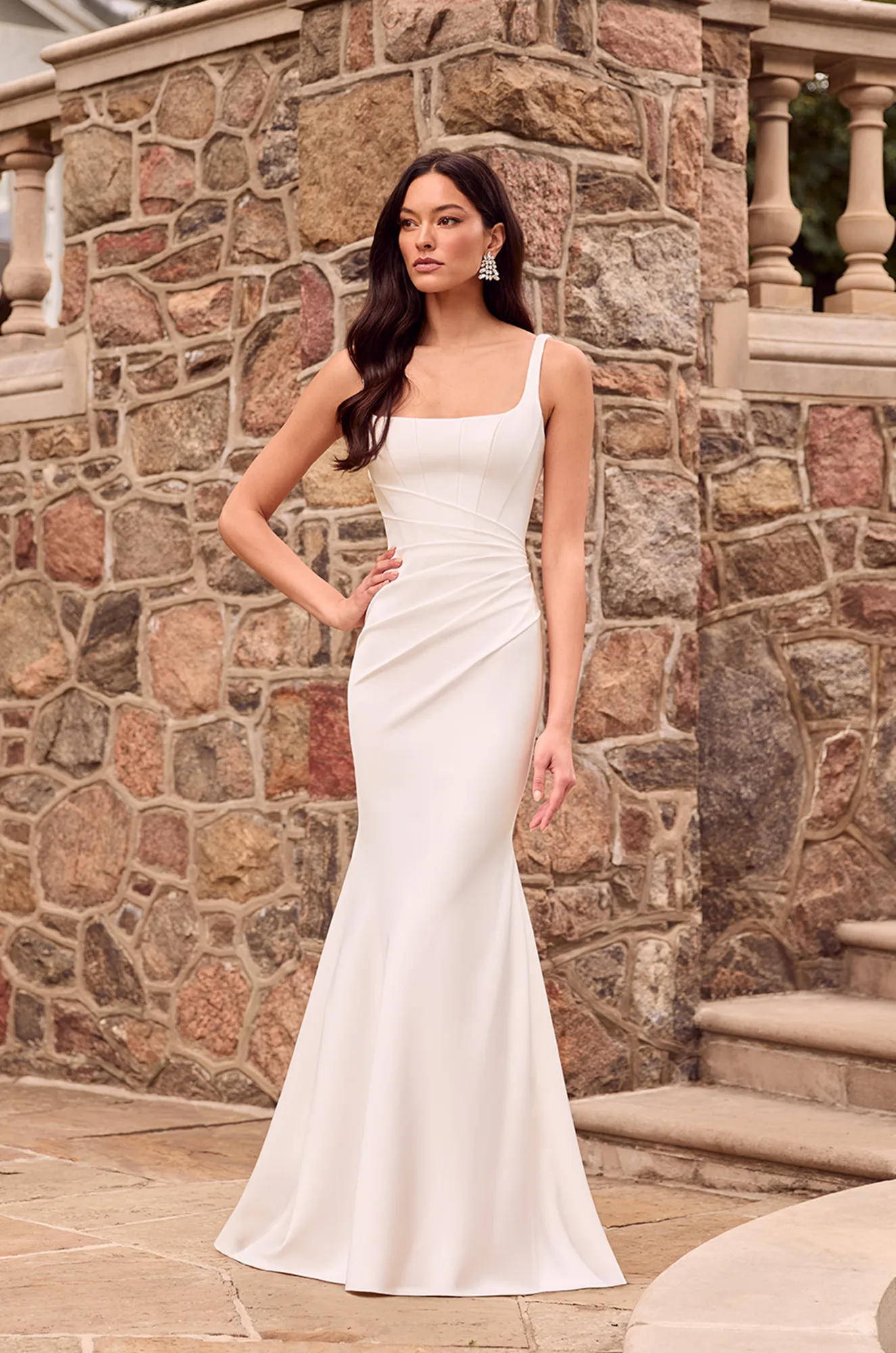 Fitted ivory gown with square neckline, ruched waist detail, and flared hem, offering a refined, modern bridal silhouette.