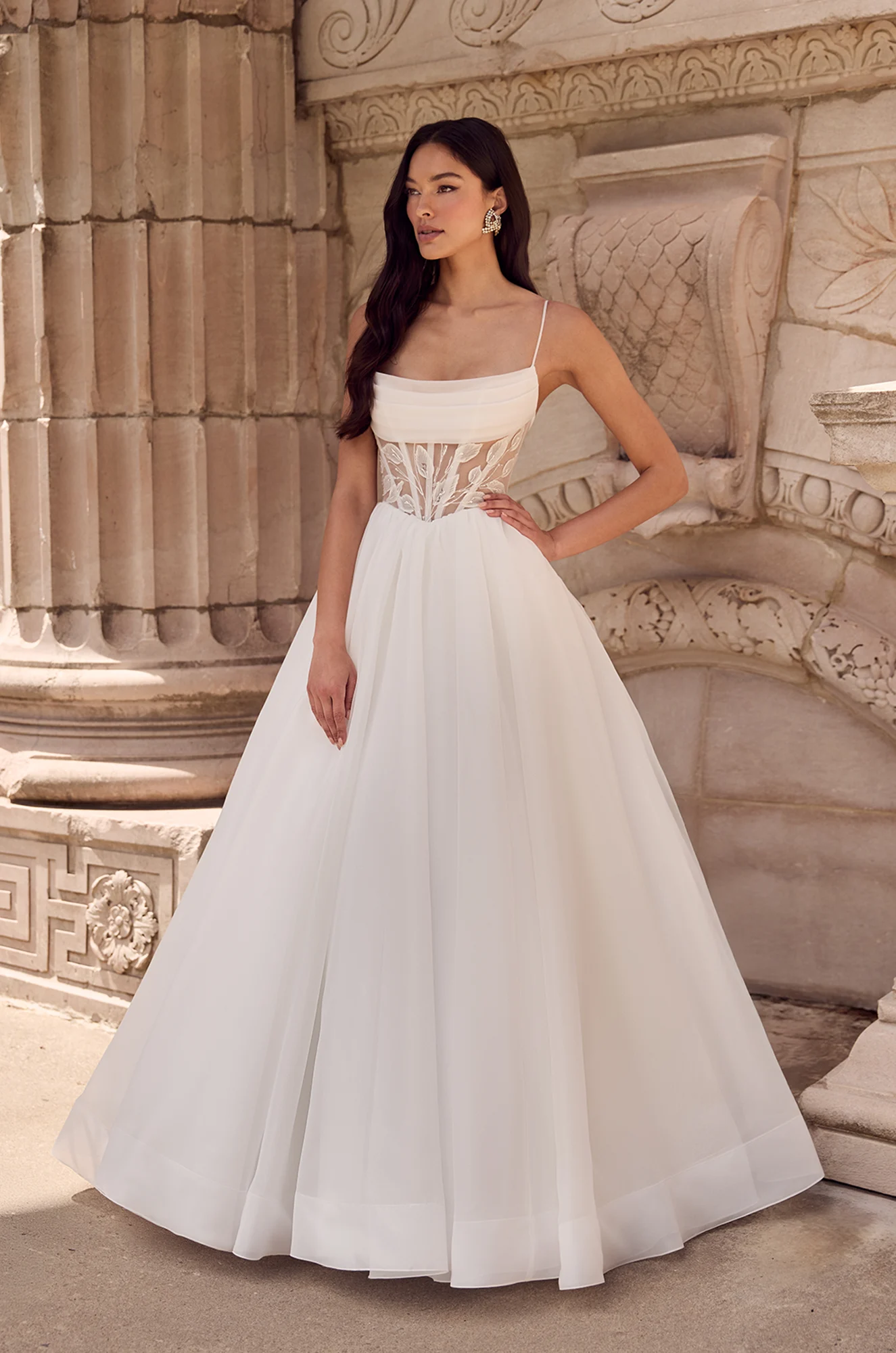 A-line gown with thin straps, sheer corset bodice featuring lace details, and full layered tulle skirt.