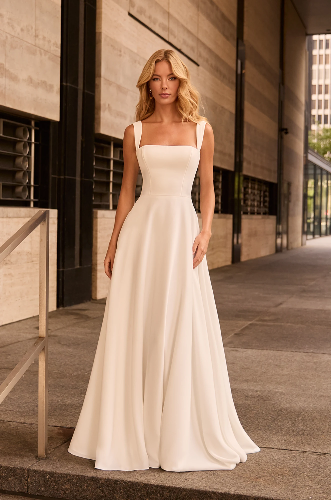 Modern A-line wedding dress with square neckline, wide straps, structured bodice, and smooth flowing satin skirt.