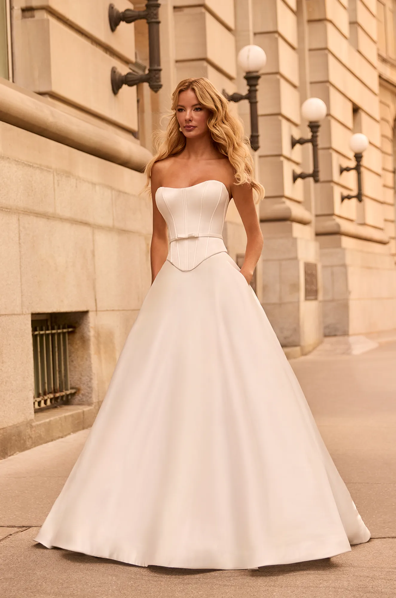 Strapless satin gown with a fitted ruched bodice and voluminous A-line skirt, creating a classic, elegant silhouette.