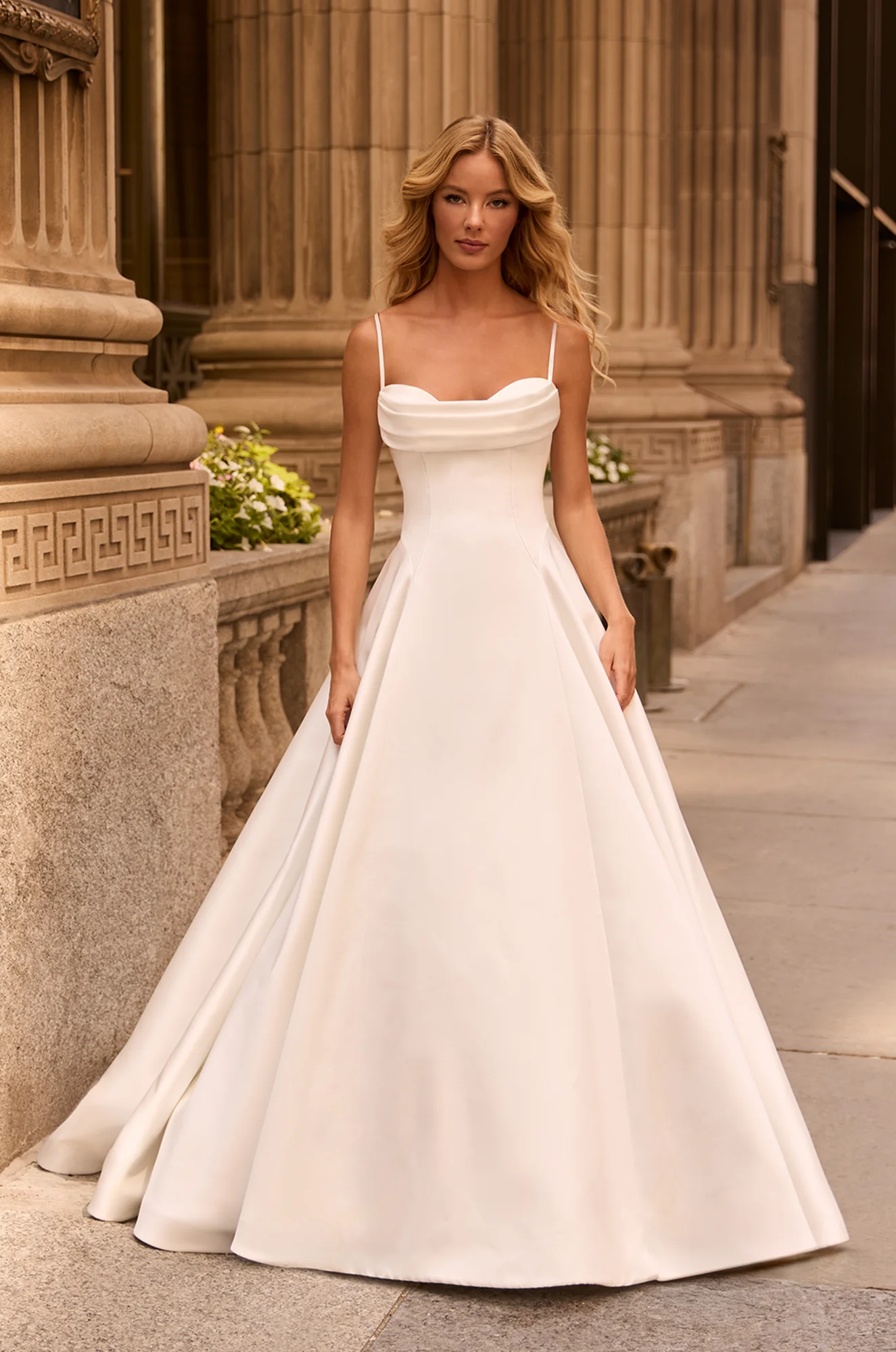 Elegant A-line gown with thin straps, draped cowl neckline, fitted bodice, and full satin skirt with structured volume.