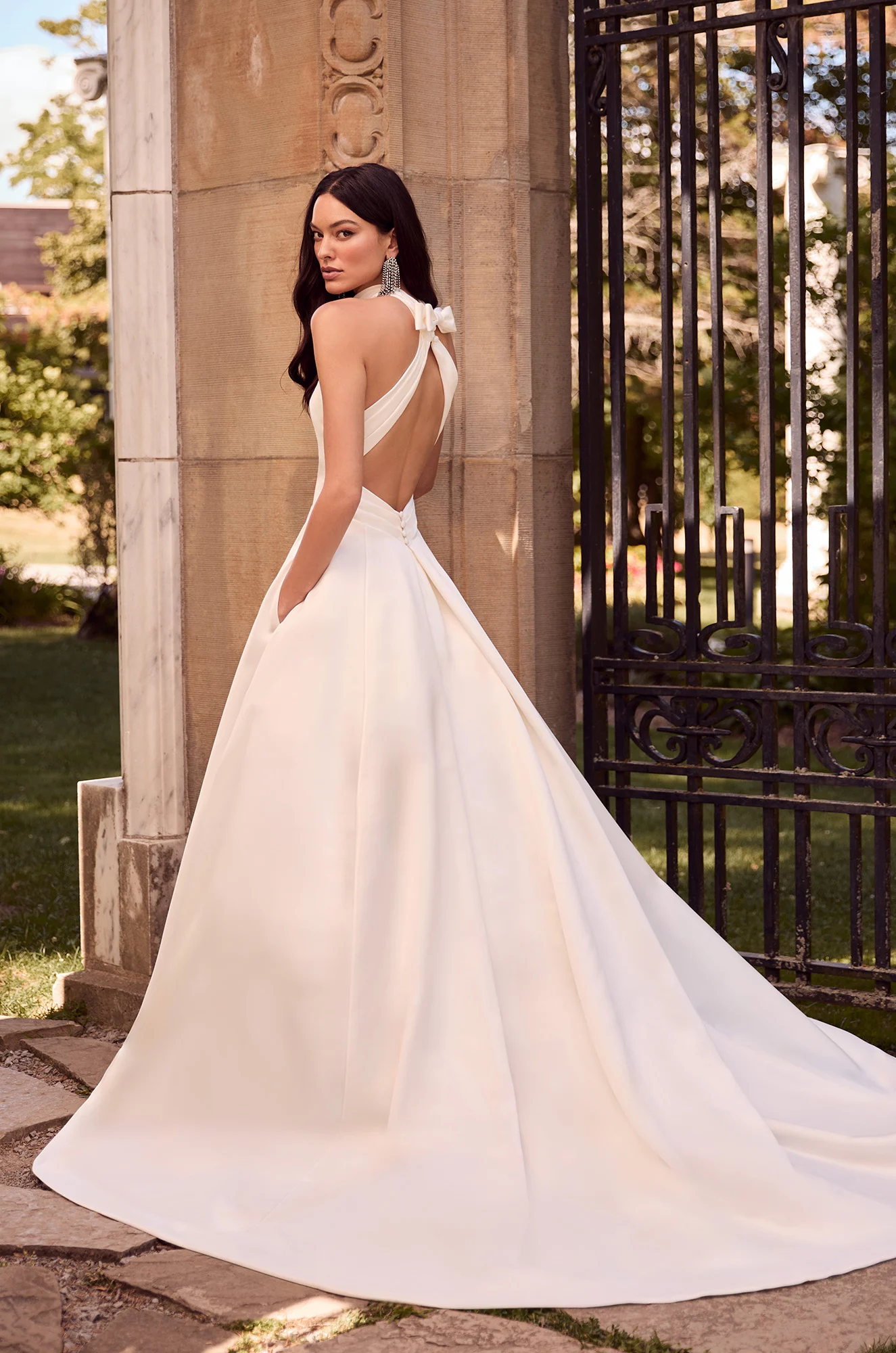 Sleek satin A-line gown featuring a halter neckline, open back with bow accent, and a long, graceful train.