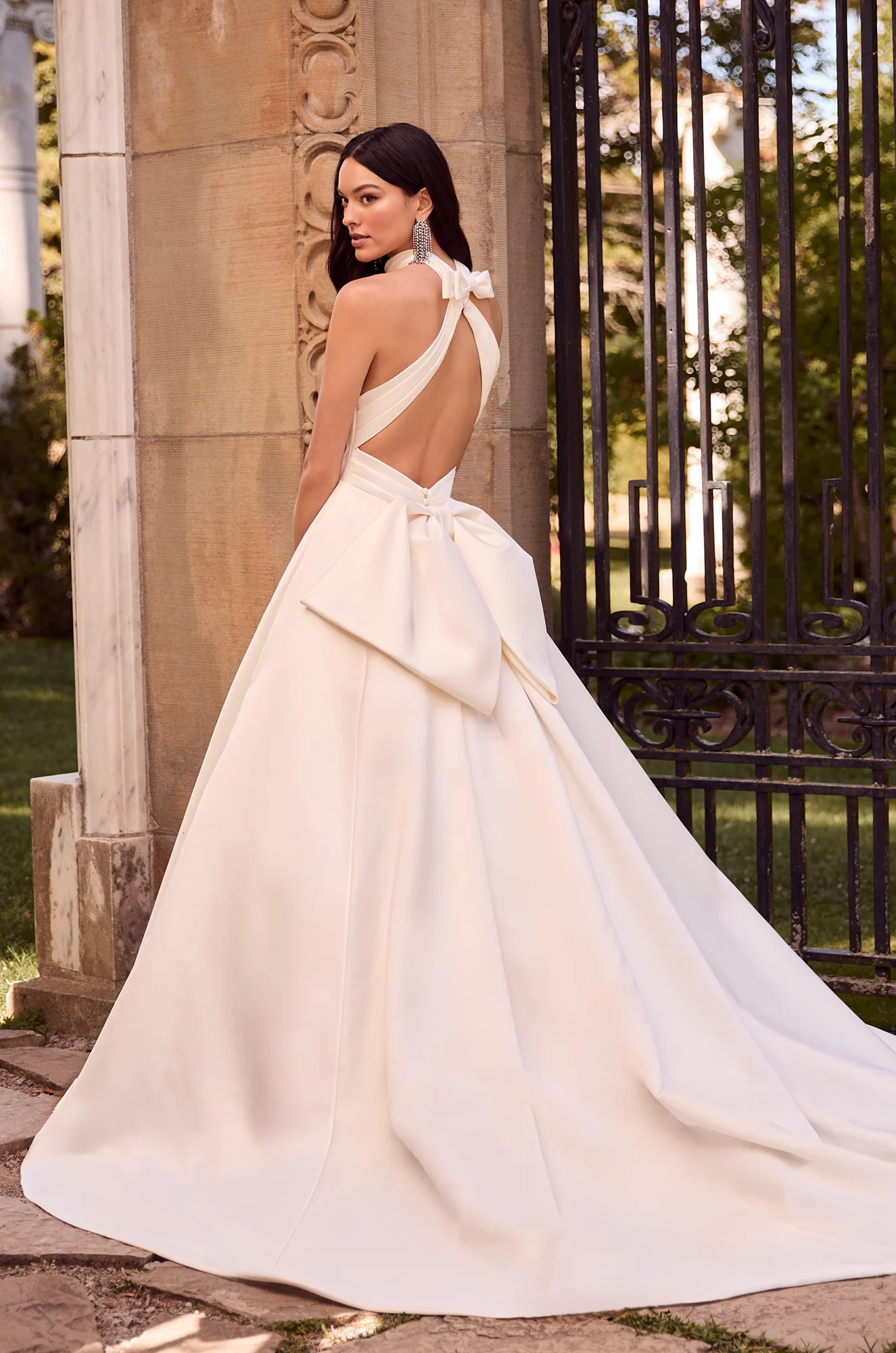 Wedding dress back view showing halter neckline and voluminous satin ball gown silhouette with large bow.