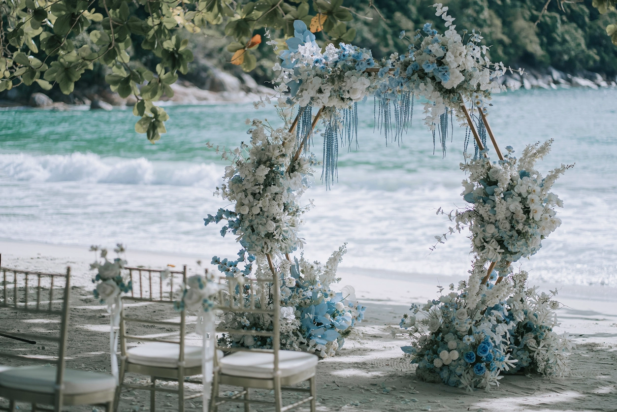Elegant beach wedding ceremony setup with floral arch and ocean backdrop—ideal inspiration for beach bridal gowns and destination weddings.
