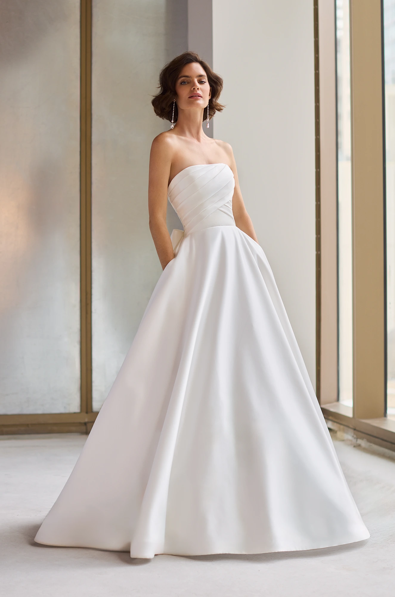 Satin gown with a straight neckline and strapless pleated bodice, and an A-line skirt with pockets.