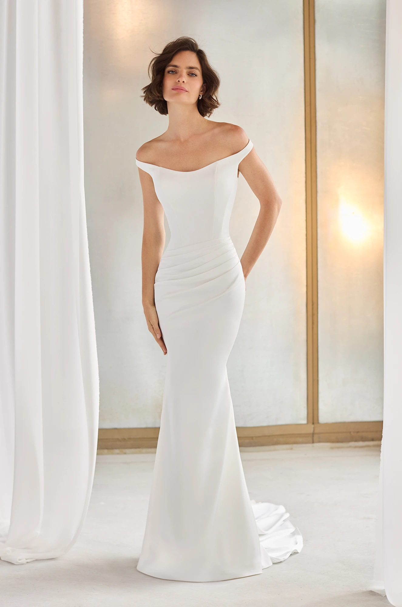 Off the shoulder Charmeuse gown with an asymmetric waistline and draped fit and flare skirt.
