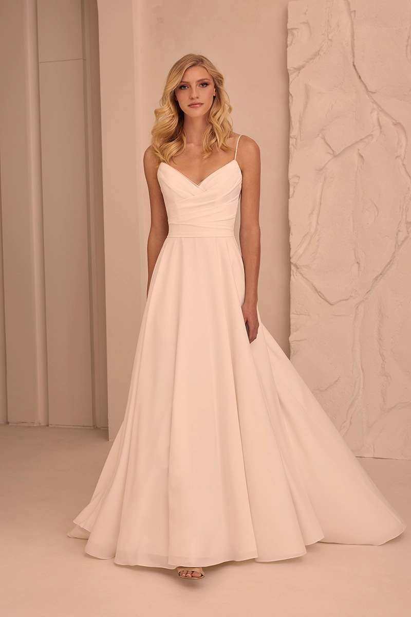 Simple A-line wedding gown with soft V-neck draped bodice, thin straps and full flowing skirt in crepe fabric.
