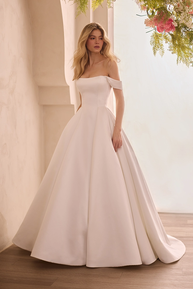 Satin princess seam gown with scoop neckline on strapless bodice and detachable draped sleeves, with a full A-line skirt with pockets.