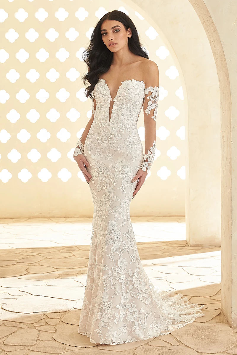 Strapless floral lace wedding dress with a plunging neckline, fit and flare skirt and illusion sleeves, in an arched interior.