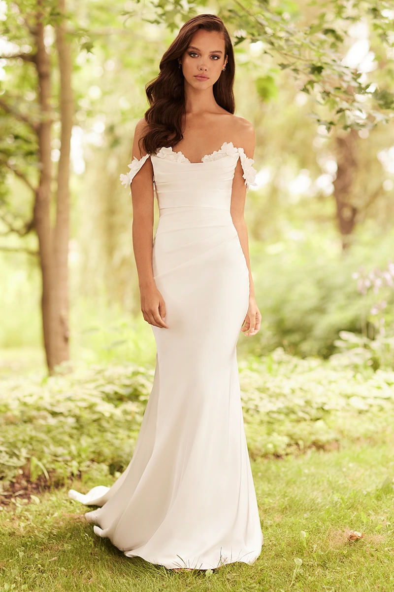 Off-the-shoulder satin wedding gown with 3D lace flowers, ruched fitted bodice, and sleek fit and flare silhouette.