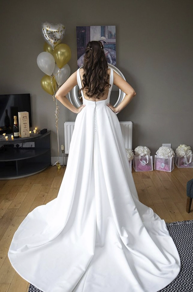 Back of bride in low open back A-line gown with a buttoned back posing in a living room with decorations.