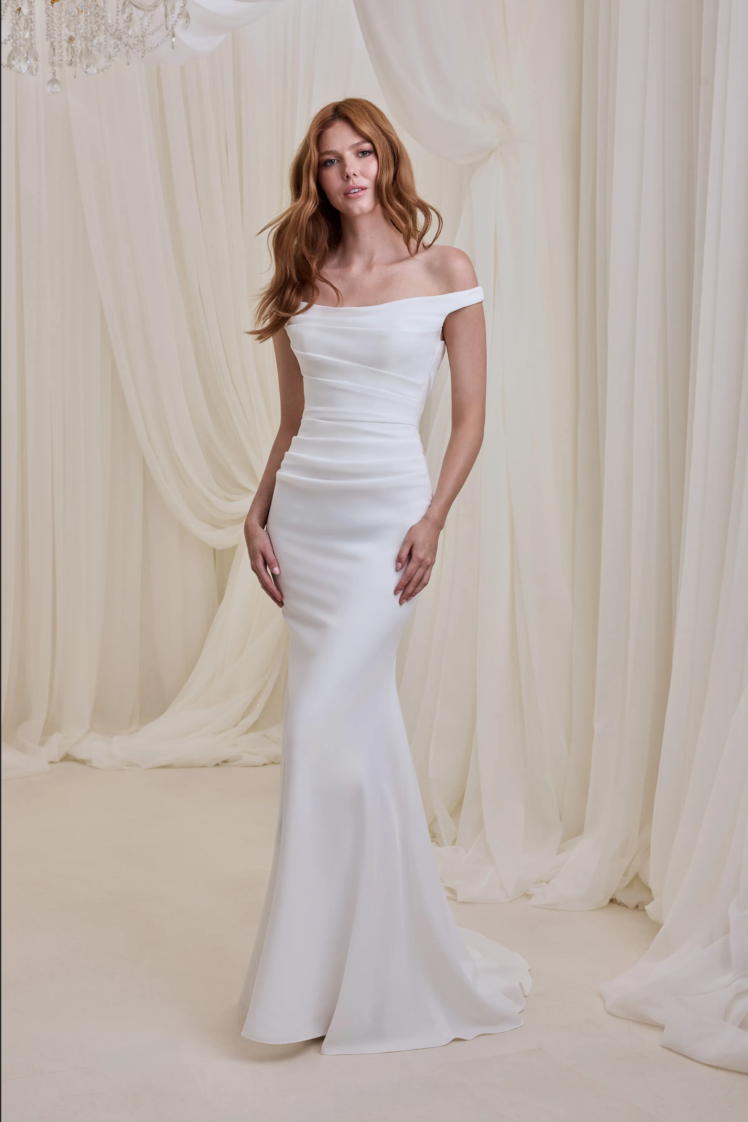 Off the shoulder Crêpe gown with a draped bodice and a fit and flare skirt.