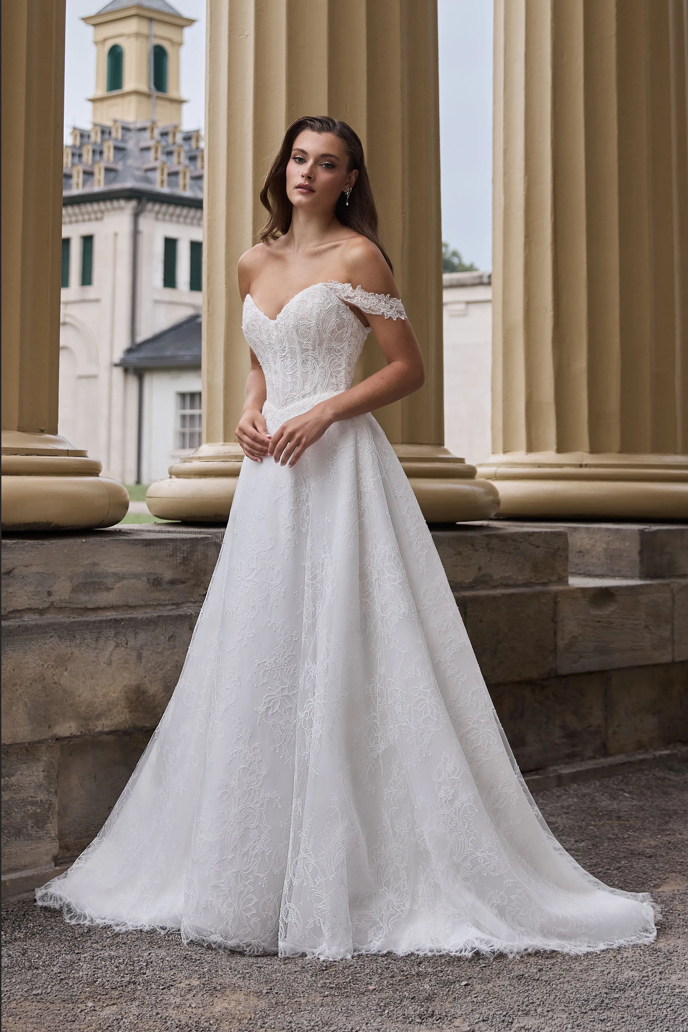 A-line Lace gown with a sheer strapless bodice and draped lace sleeves, with a Basque waistline and lace skirt.
