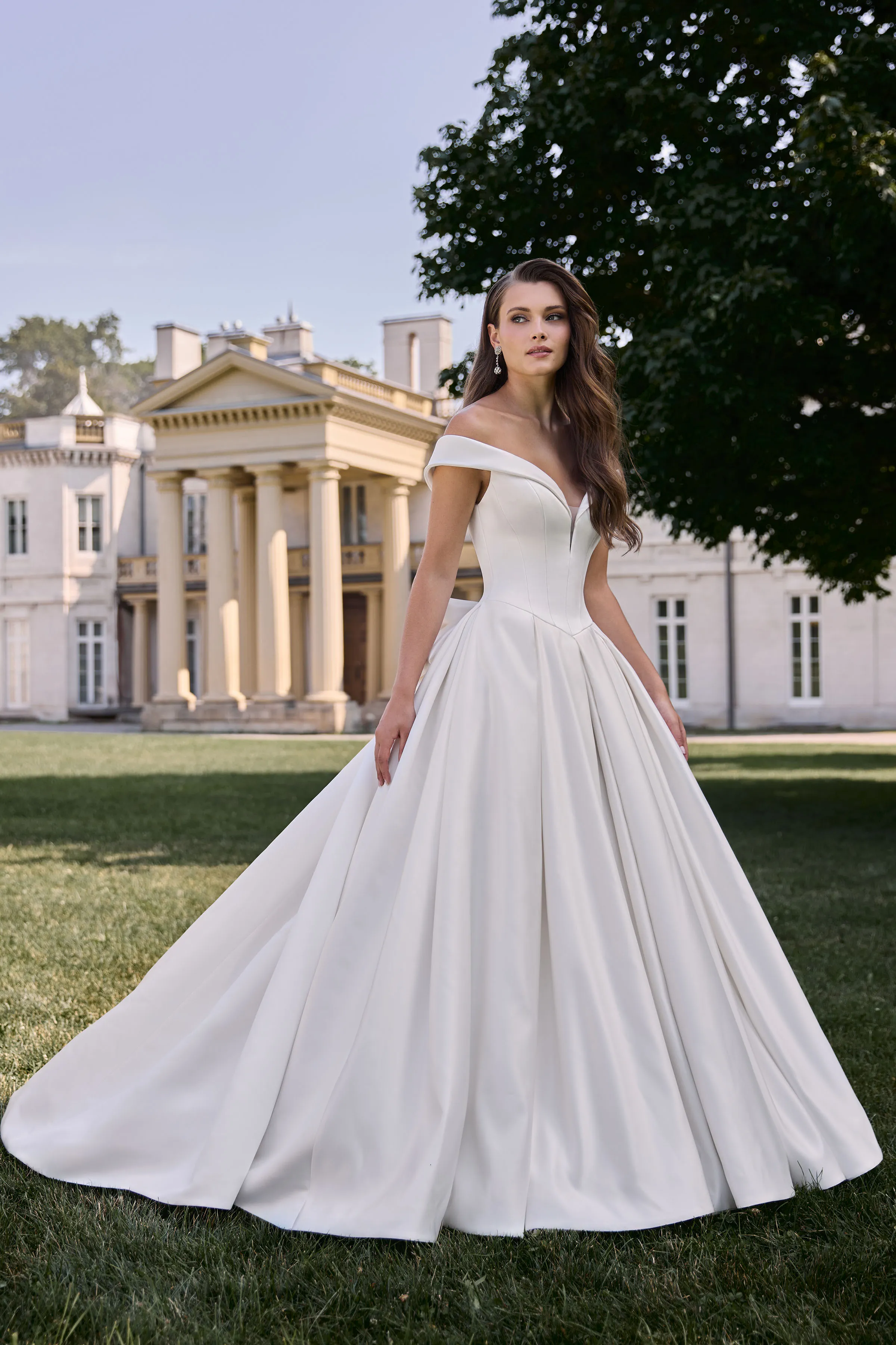 Satin gown with off the shoulder plunging neckline and seamed bodice with a Basque waistline, and a pleated ball gown skirt.